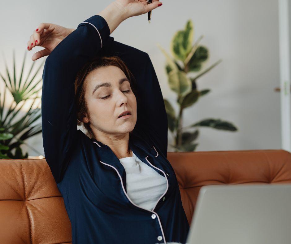 A tired author leaning back in a chair, staring out a window while taking a break from writing a book.